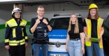 Vier junge Menschen in unterschiedlichen Berufskleidungen der Verbandsgemeindeverwaltung stehen vor einem Fahrzeug des Ordnungsamts und lächeln in die Kamera.