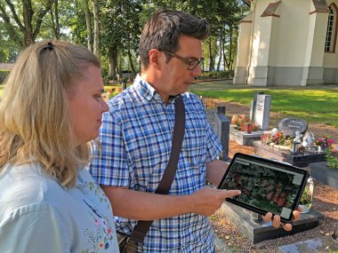 Bild zeigt einen Mann und eine Frau mit Tablet auf dem Friedhof