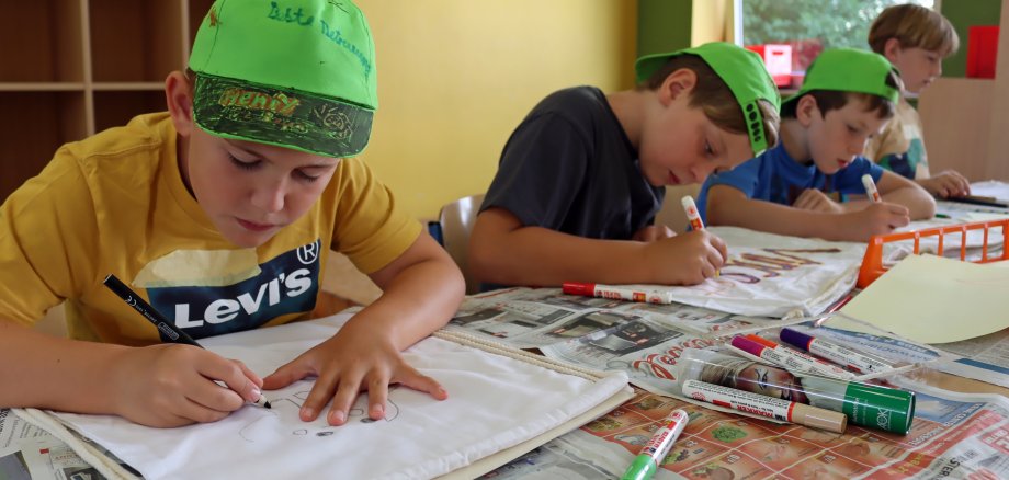 Vier Jungs beim Bemalen von Stofftaschen.