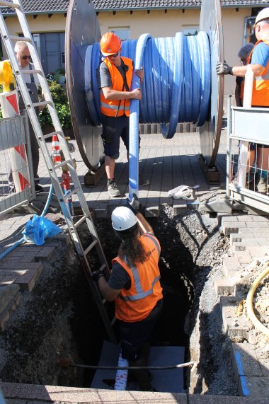 Arbeiter ziehen den Inliner von einer großen Rolle und fädeln ihn in die alte Leitung.