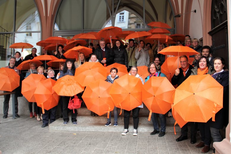 Mitarbeiterinnen und Mitarbeiter der VG Montabaur mit orangenen Schirmen vor dem Alten Rathaus.