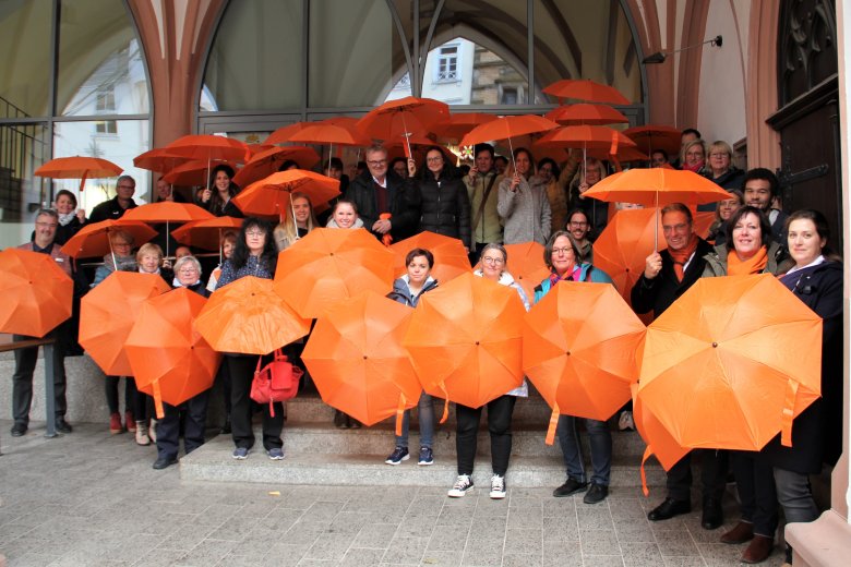 Mitarbeiterinnen und Mitarbeiter der VG Montabaur mit orangenen Schirmen vor dem Alten Rathaus.