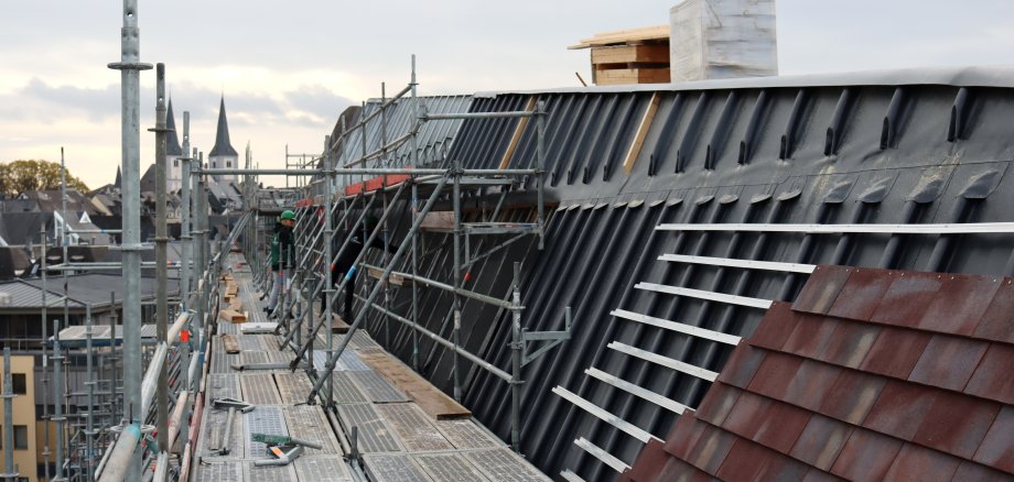 Bauarbeiter verkleiden das Dach des Verbandsgemeindehauses mit Ziegel.
