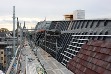 Bauarbeiter verkleiden das Dach des Verbandsgemeindehauses mit Ziegel.
