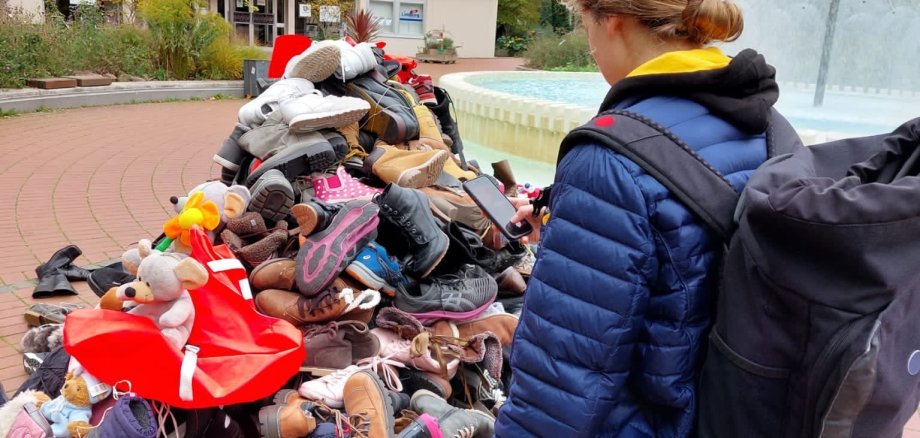 Eine Frau steht vor einem großen Schuhhaufen, der als Mahnwache galt.