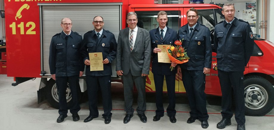 Die Verantwortlichen der Feuerwehr stehen vor einem Feuerwehrauto.