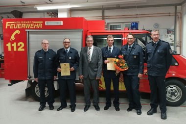 Die Verantwortlichen der Feuerwehr stehen vor einem Feuerwehrauto.