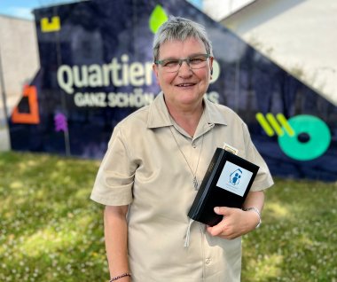 Schwester Barbara Spiegelhoff steht mit ihrem Terminplaner in der Hand im Quartier Süd.