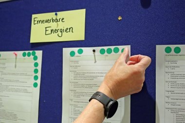 Eine Hand klebt Punkte auf ein Blatt Papier. 