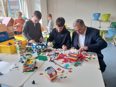 Der Erste Beigeordnete Andree Stein und zwei Jungs basteln mit Legobausteinen.