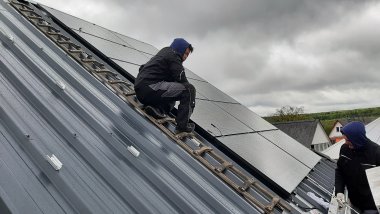 Zwei Männer installieren eine Solaranlage auf einem Dach.