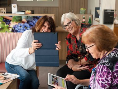 Drei Frauen haben ihren Spaß bei der Nutzung von Tablets.