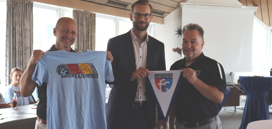 Vertreter des South Carolina United Football Clubs überreichen Bürgermeister Ulrich Richter-Hopprich einen Wimpel und ein Trikot.