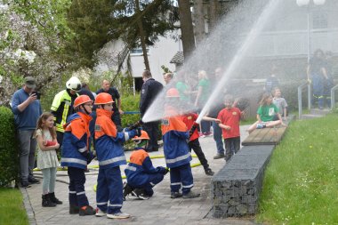 Die Nachwuchsfeuerwehr spritzt Wasser mit dem Feuerwehrschlauch.