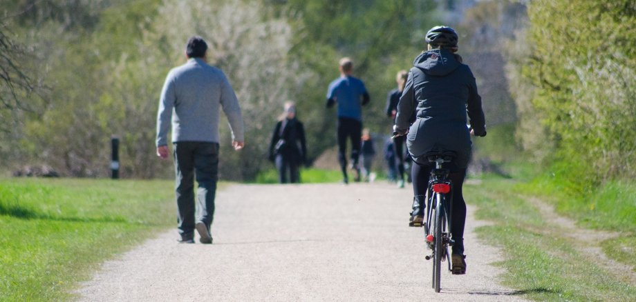 Fahrradfahrer und Fußgänger in einem Park.