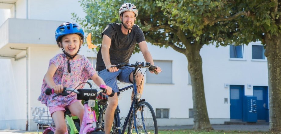 Ein Kind und ein Mann sind mit dem Fahrrad unterwegs.