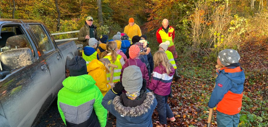 Die Kinder lauschen den Erklärungen des Försters.