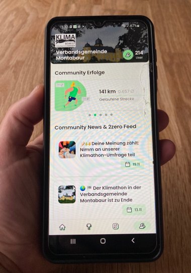 Eine Hand hält ein Handy mit der Klimathon-App auf dem Display.