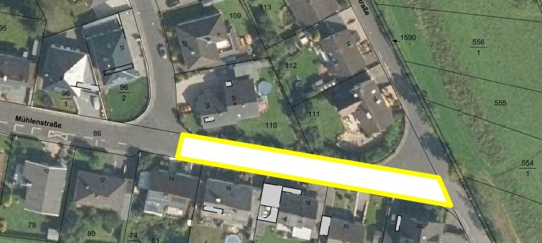Ein Luftbild zeigt Häuser, Grundstücke und Straßen. Ein Straßenabschnitt ist weiß markiert mit gelber Umrandung.