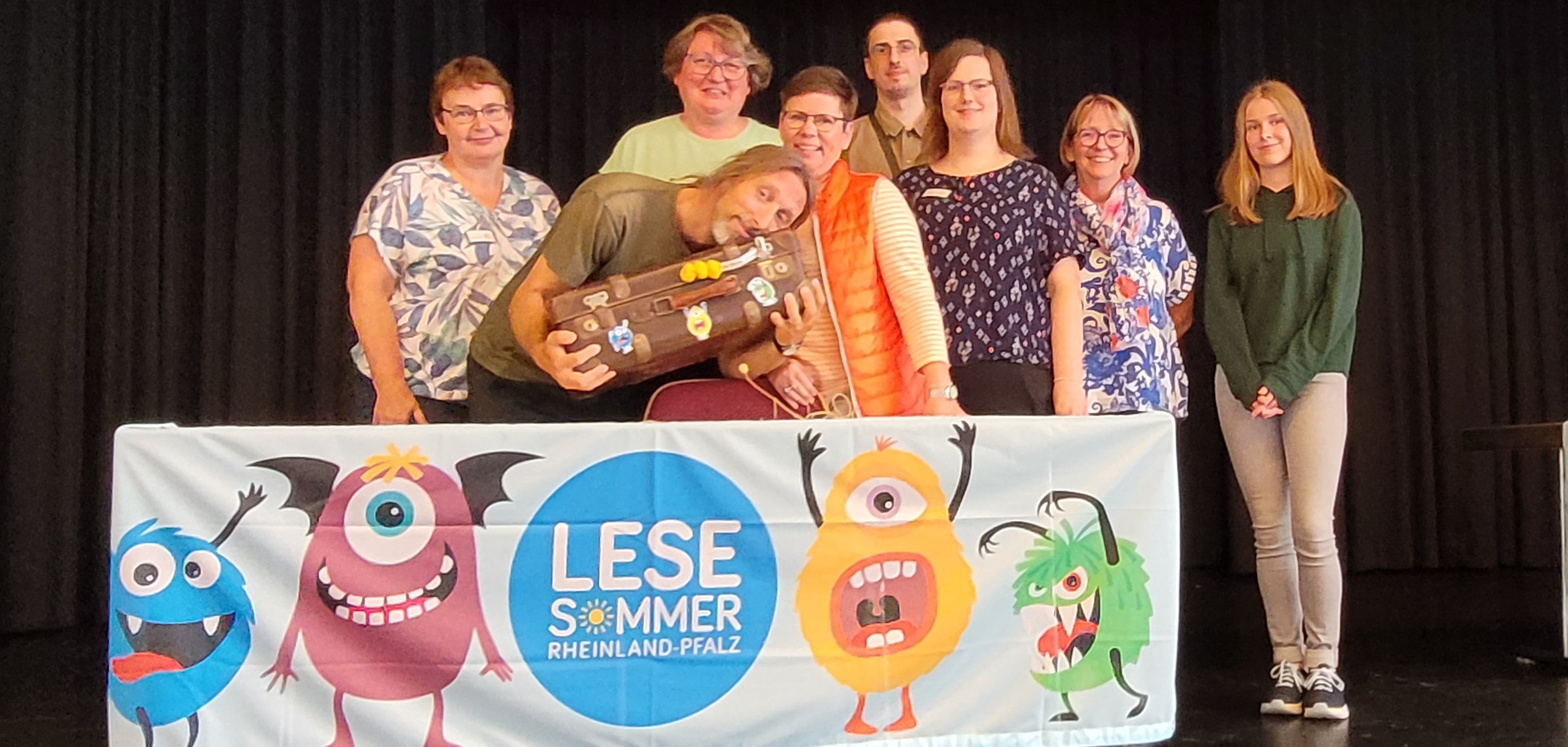 Sechs Frauen und zwei Männer vor dem Banner "Lesesommer Rheinland-Pfalz"