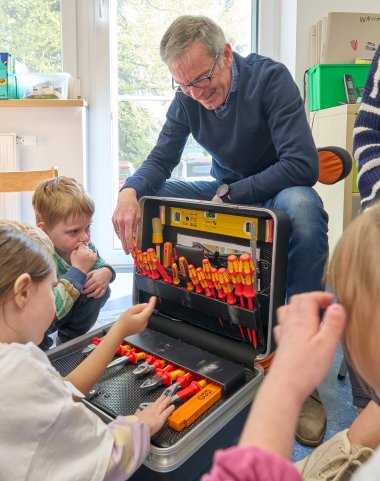 Nobert Rausch zeigt den Kindern seinen Werkzeugkoffer.