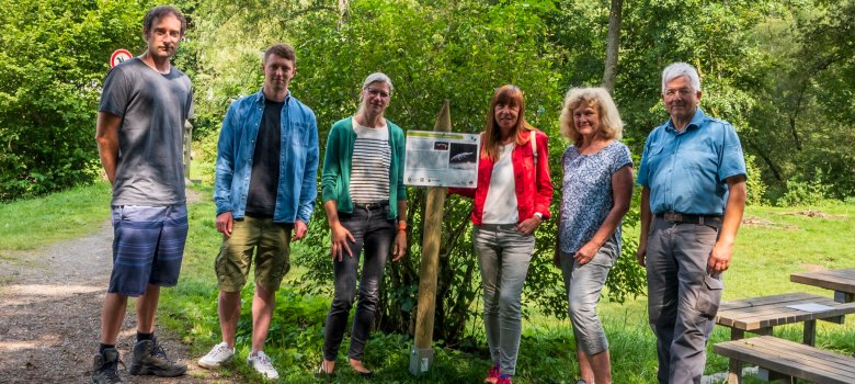 Mehrere Personen stehen an einer der neuen Tafeln, die am Wegesrand des Gelbachtrails informieren.