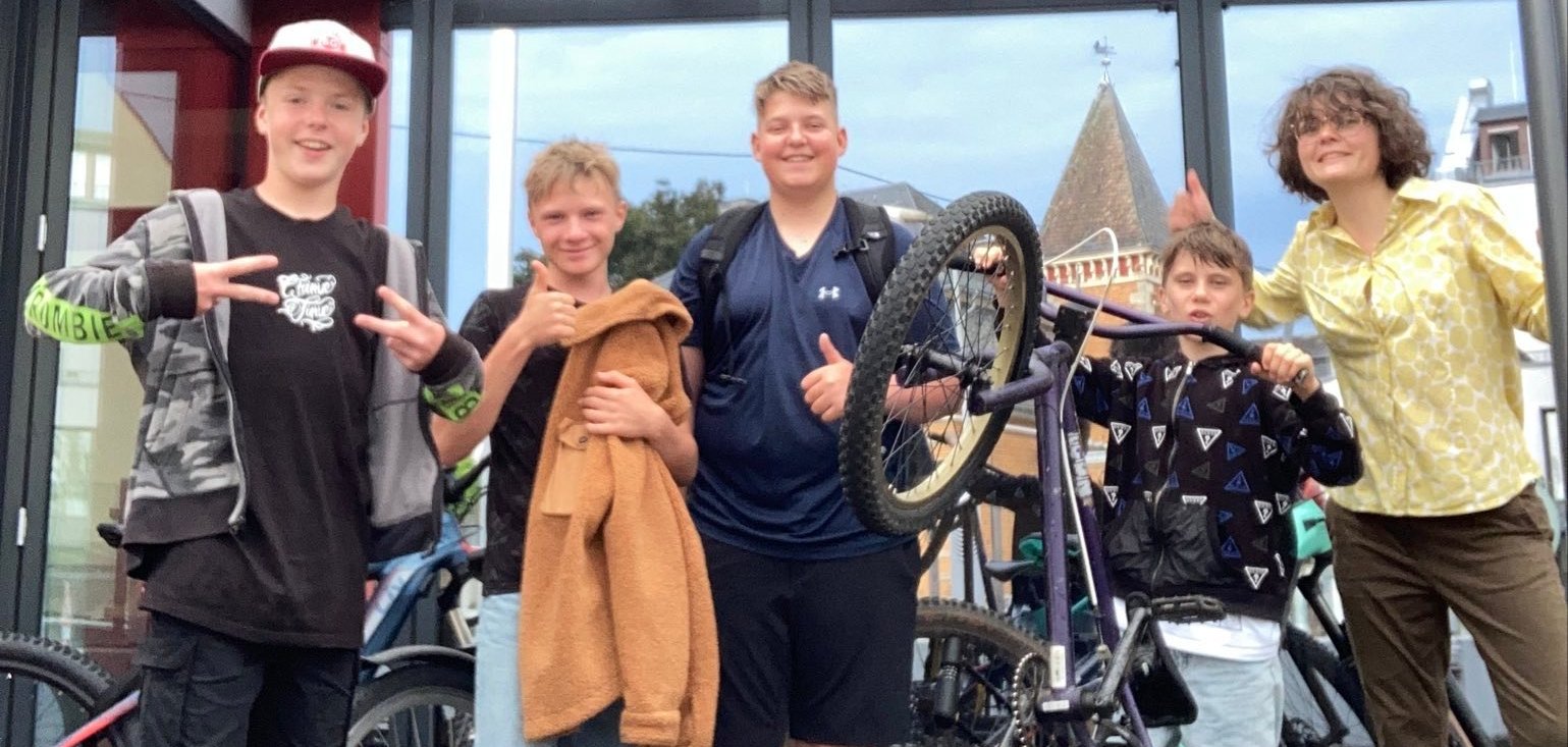 JumaZu-Leiterin Larissa Metz mit vier Jugendlichen und ihren Fahrrädern zeigen dne Daumen nach oben.