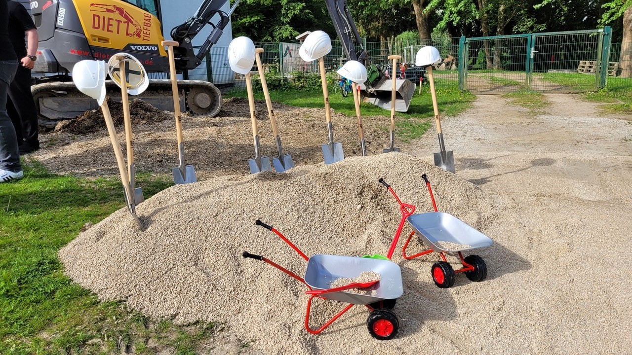 Spaten, Helme und kleine Schubkarren stehen bereit für den Spatenstich.