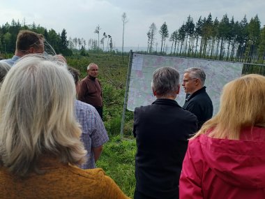 Bild zeigt Wandergruppe im Wald vor einer Karte.