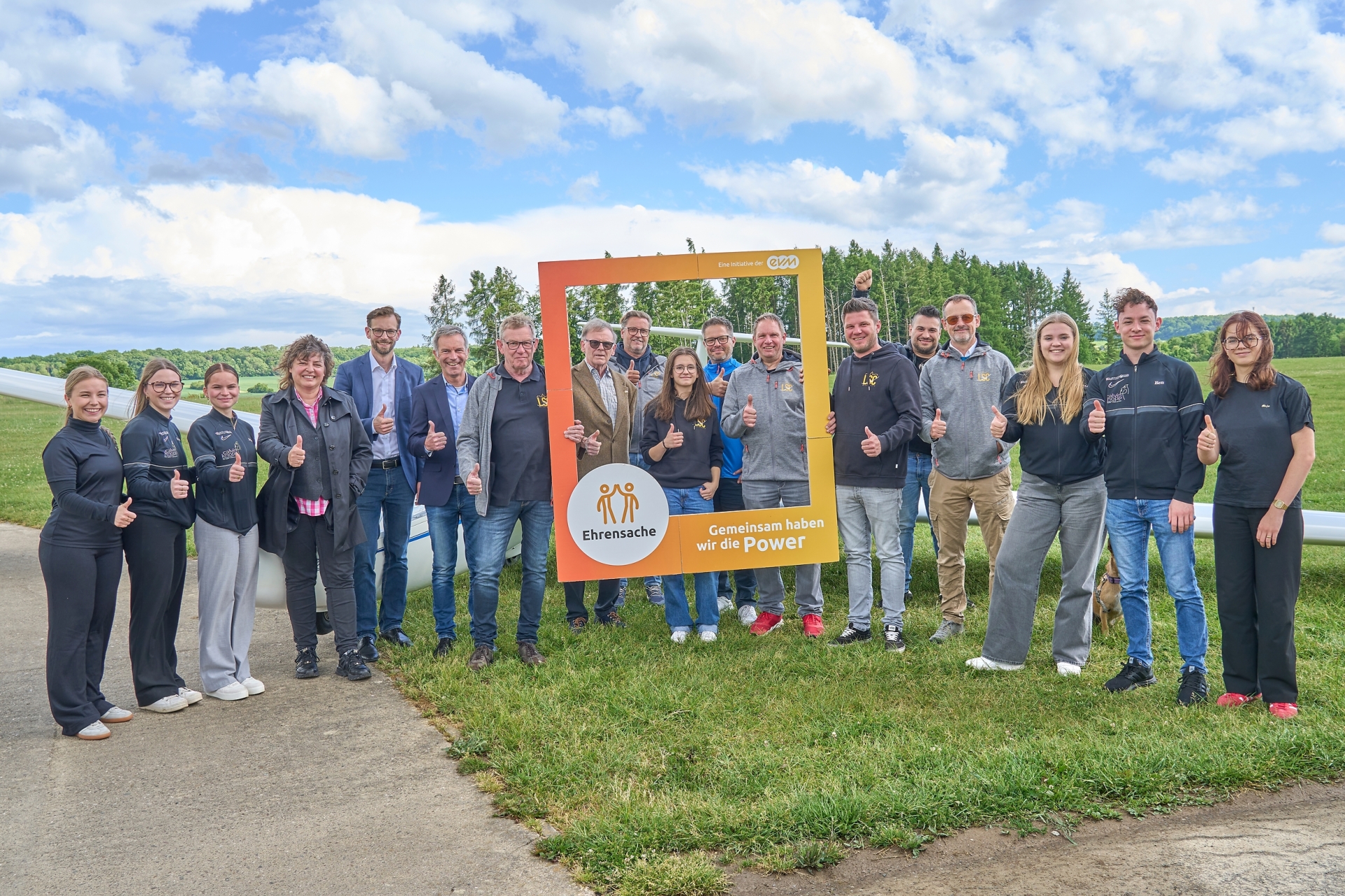 Mehrere Menschen stehen auf dem Flugplatz Montabaur zusammen, während Norbert Rausch von der evm und VG-Bürgermeister Ulrich Richter-Hopprich eine Spende an die Vertreter von vier Vereinen überreichen. Stadtbürgermeisterin Melanie Leicher und Ortsbürgermeister Tobias Reusch aus Nentershausen sind ebenfalls Teil der Gruppe.