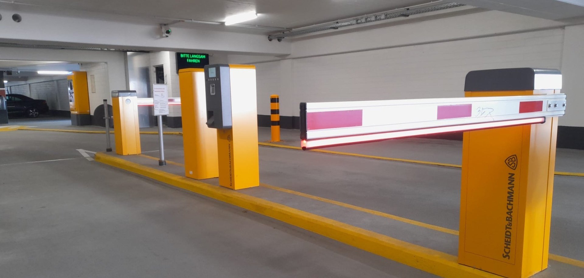 Einfahrt einer Tiefgarage mit Schranke und modernen Erfassungssystemen.