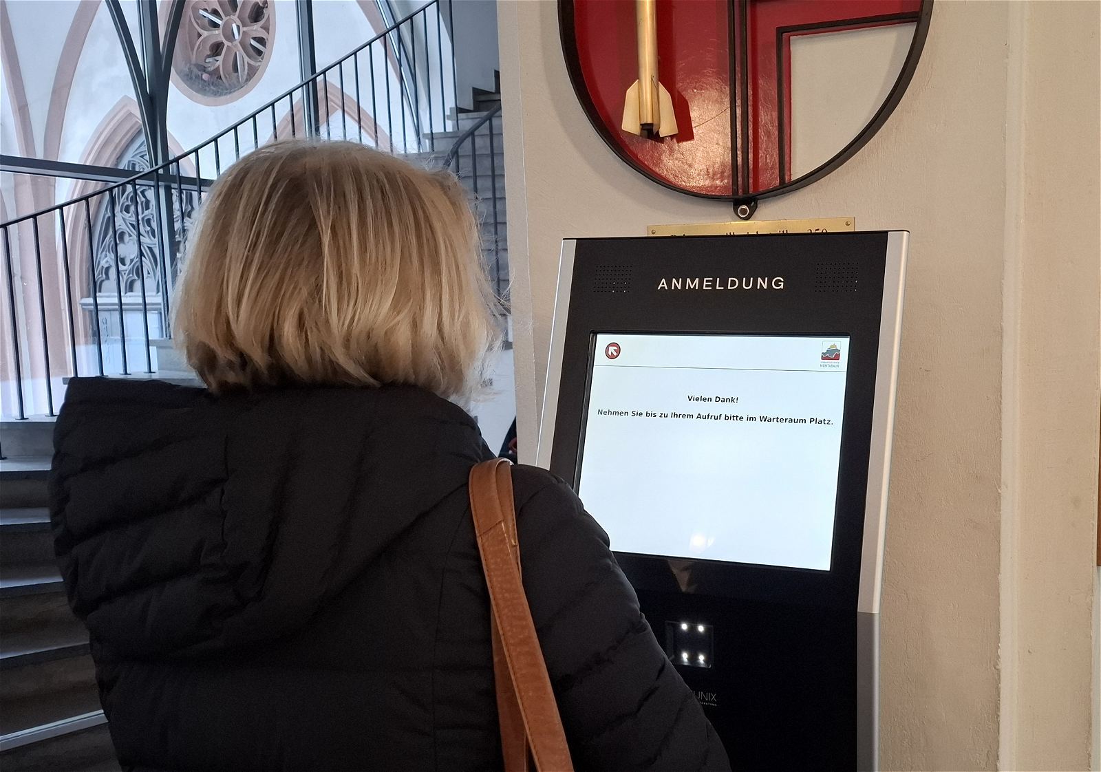 Eine Bürgerin meldet sich am Terminal im Eingangsbereich an
