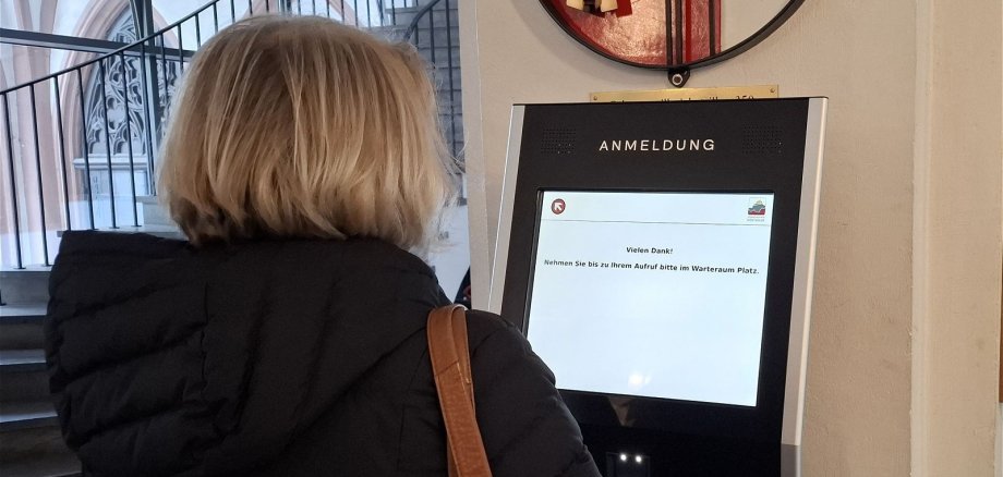 Eine Bürgerin meldet sich am Terminal im Eingangsbereich an