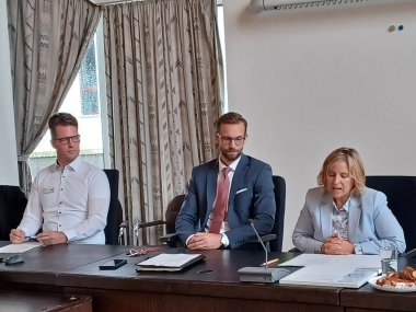 Klimaschutzministerin Katrin Eder sitzt mit Bürgermeister Ulrich Richter-Hopprich und Vertretern der Verbandsgemeinde Montabaur im Sitzungssaal während der offiziellen Übergabe des Kom.EMS-Zertifikats.