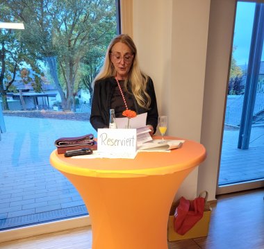 Kita-Leiterin Andrea Fuß spricht bei der Eröffnungsfeier hinter einem orangefarbenen Stehtisch.