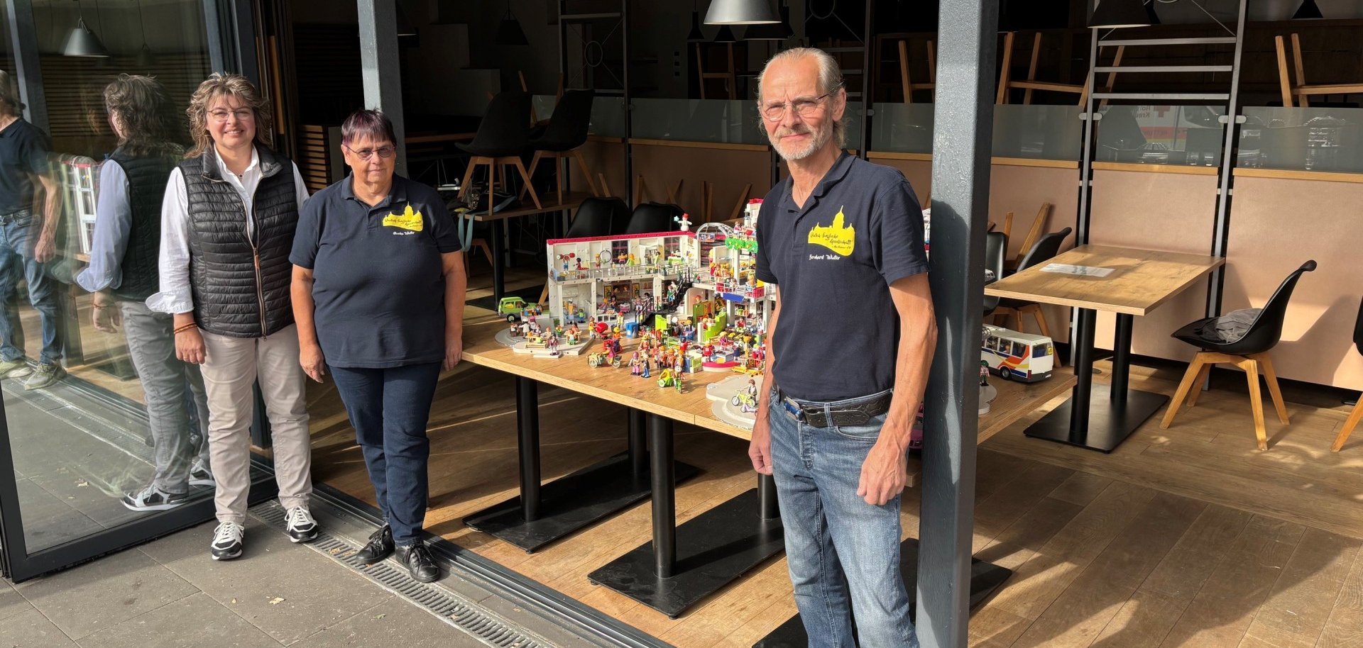 Mit ihren Playmobil-Welten bringen Monika und Bernd Winter Leben in die wegen Baumaßnahmen geschlossene Stadthalle. Stadtbürgermeisterin Melanie Leicher (l.) freut sich über den bunten Hingucker im Fenster des Restaurants.