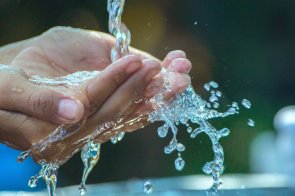 Hände unter einem Wasserstrahl.