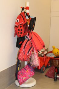 Das Bild zeigt eine Garderobe im Kindergarten mit Fahrradhelm, Rucksack und Regenjacke
