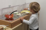 Das Bild zeigt ein Kindergartenkind vor dem Verpflegungsangebot