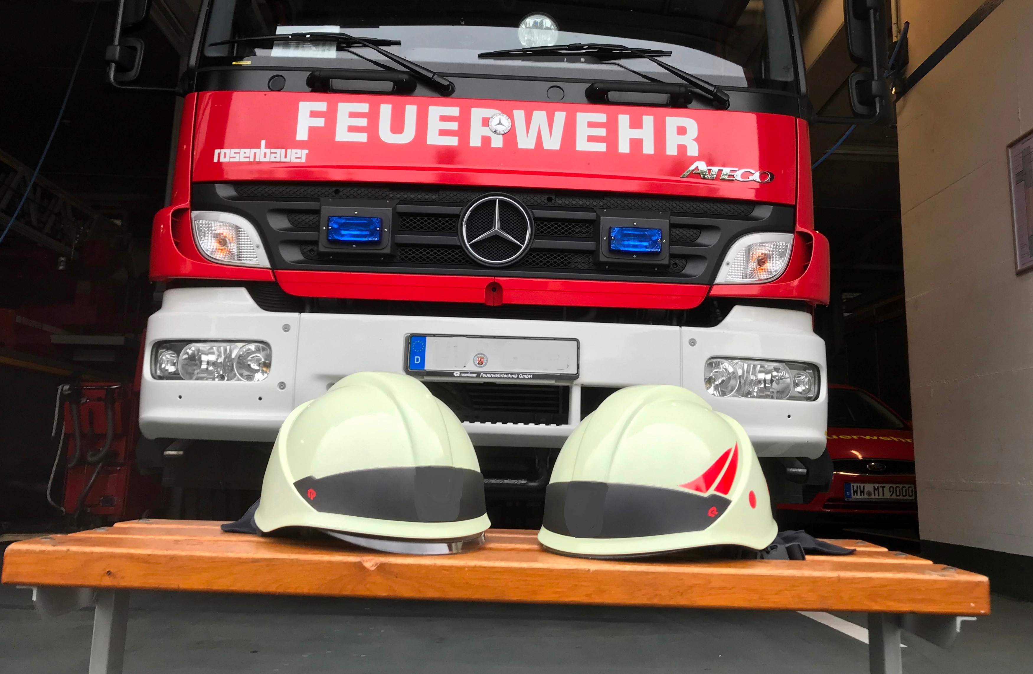 Das Bild zeigt ein Feuerwehrfahrzeug und Feuerwehrhelme.