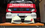Das Bild zeigt ein Feuerwehrfahrzeug und Feuerwehrhelme
