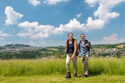 Bild zeigt eine Frau und einen Mann beim Wandern über Felder Bild zeigt eine Frau und einen Mann beim Wandern über Felder