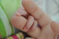 Bild zeigt Finger von Baby und Erwachsenem