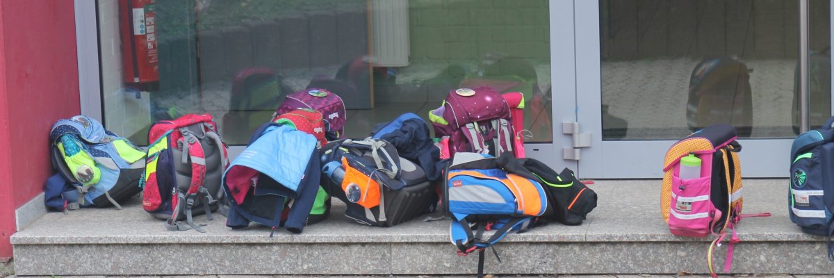 Schulranzen liegen vor der Tür zur Schule